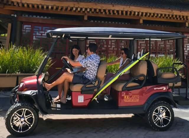 Clients riding a red six-seat golf cart
