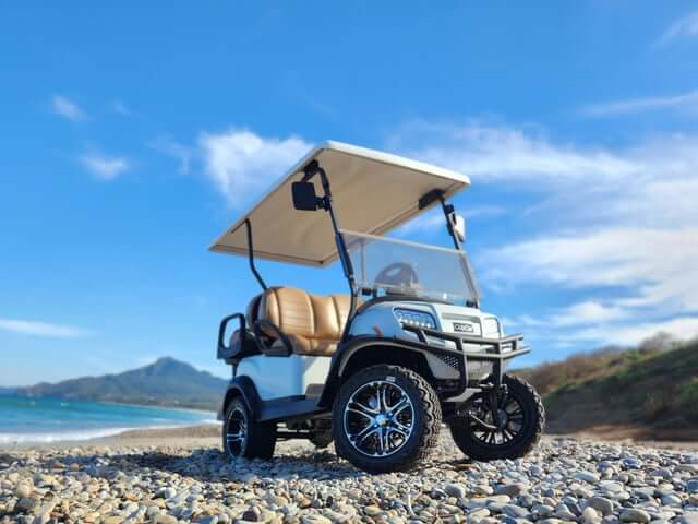 White 4 passenger golf cart on a pebble beach